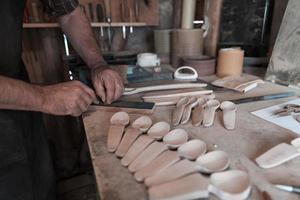 mani intaglio cucchiaio a partire dal Di legno, Lavorando con scalpello vicino su. di legno officina. processi di fabbricazione di legno cucchiaio foto