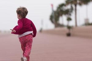 carino poco ragazza su il lungomare di il mare foto