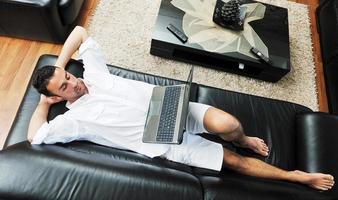 ritratto di un' rilassato giovane tipo utilizzando il computer portatile a casa foto