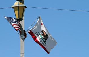 americano bandiera e il stato bandiera di California agitando nel il vento foto
