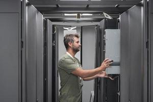 esso ingegnere Lavorando nel il server camera o dati centro il tecnico mette nel un' cremagliera un' nuovo server di aziendale attività commerciale mainframe supercomputer o criptovaluta estrazione azienda agricola. foto