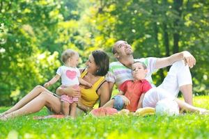 felice giovane coppia con i loro bambini si divertono al parco foto