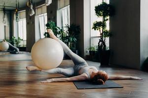 donna che fa esercizi addominali con palla in forma sul tappetino yoga foto