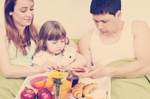 contento giovane famiglia mangiare prima colazione nel letto foto