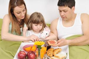 contento giovane famiglia mangiare prima colazione nel letto foto