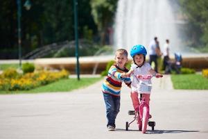 ragazzo e ragazza nel parco apprendimento per cavalcata un' bicicletta foto