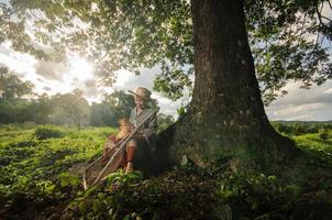 asiatico nonna pescatore con il netto bambù sotto il grande albero foto