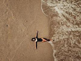 aereo superiore Visualizza giovane donna dire bugie su il sabbia spiaggia e onde foto