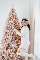 giovane donna nel un elegante vestito vicino il Natale albero foto