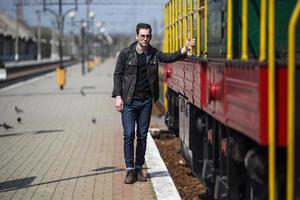 un' uomo vestito nel jeans su il sfondo di il treno e il stazione foto