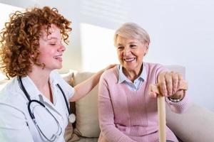 vicino positivo relazione fra anziano paziente e Caregiver. contento anziano donna parlando per un' amichevole Caregiver. giovane bella badante e più vecchio contento donna foto