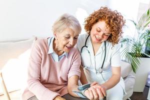badante misurazione sangue pressione di anziano donna a casa. genere badante misurazione il sangue pressione di un' contento anziano donna nel letto nel il assistenza infermieristica casa. foto