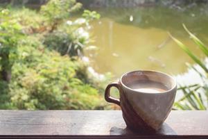 un' tazza di caldo cacao di il di legno balcone su natura sfondo per il nuovo mattina. foto