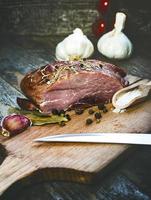 carne di maiale affumicata con erbe, spezie e coltello su tavola di legno.