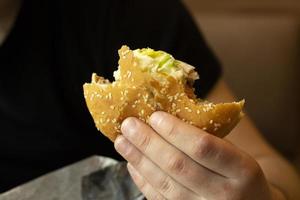 Sandwich nel mano. ciambella con sesamo. Grasso il pranzo. cibo nel il ristorante. foto