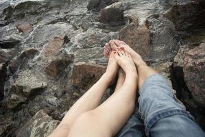 il tipo e il ragazza siamo riposo su il mare. piedi di il acqua foto