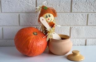 un' spaventapasseri con un' di legno cucchiaio, a argilla pentola e un' zucca su un' bianca sfondo.halloween e ringraziamento giorno concetto foto