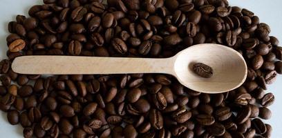aromatico caffè fagioli nel un' di legno cucchiaio, caffè fagioli per il produzione di delizioso caffè. totale caffè fagioli per macinazione foto
