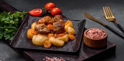 Manzo carne e verdure stufato su un' nero piatto con arrostito patate foto