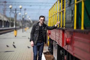 un' uomo vestito nel jeans su il sfondo di il treno e il stazione foto