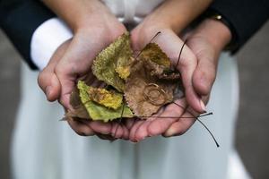 sposa e sposo Tenere nozze anelli e autunno le foglie nel mani foto