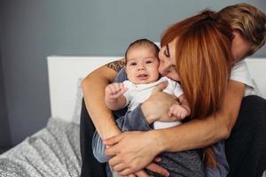 contento famiglia con neonato bambino su il letto foto