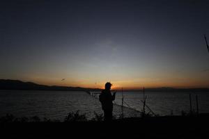 silhouette di un' persone su il lago foto