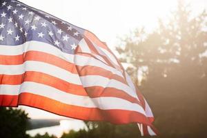 veterani giorno bandiera di il unito stati di America. americano bandiera volante su il sfondo di il ambientazione sole nel natura. foto