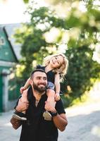 un' poco figlia si siede su il le spalle foto