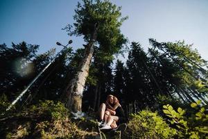 bellissimo coppia seduta nel un' foresta vicino il albero foto