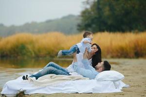 contento giovane famiglia rilassante insieme su il lago foto