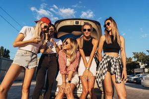 cinque giovane donne avere divertimento a il auto parco. foto