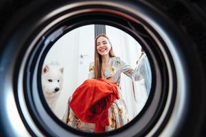 giovane donna a casa mette il vestito nel il essiccazione macchina. foto