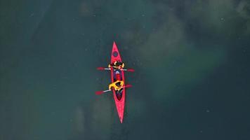 Due atletico uomo galleggia su un' rosso barca nel fiume foto