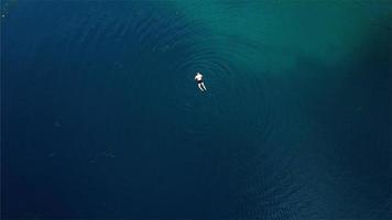 aereo Visualizza su un' nuotatore nel il turchese acqua di un' lago foto