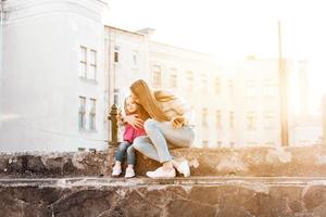 mamma e figlia sedersi insieme su il recinto foto