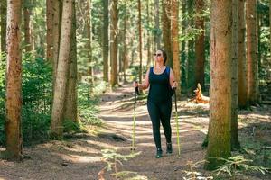 donna passeggiate attraverso il foresta su un' ben calpestato sentiero. il concetto di un' salutare vita, godendo e giocando gli sport nel natura foto