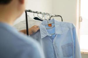 uomo è la scelta camicia nel il Abiti camera a casa. foto