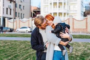 contento mamma papà e figlio abbracciare nel il parco foto