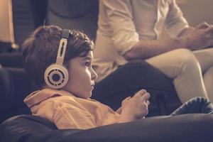 piccolo ragazzo con cuffie giocando video Giochi a casa. foto
