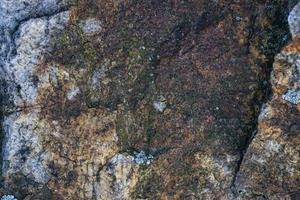 fondo grigio grezzo di struttura della roccia del granito. frammento di muro di pietra naturale foto