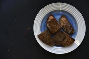 nero pane con fette su un' blu piatto. delizioso pagnotta di nero pane tagliare su avvicinamento. foto