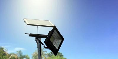 mini solare o fotovoltaico cellula pannello installato su metallo polo con proiettore portato, sfocatura nuvoloso e cielo blu sfondo, concetto per utilizzando naturale energia a partire dal il sole nel quotidiano vita di umano. foto