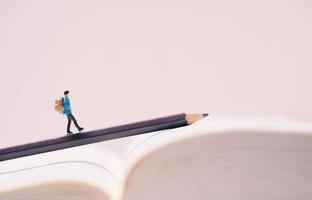 miniatura persone figure con zaino a piedi su matita e libro con copia spazio, viaggio e studia all'estero concetto foto
