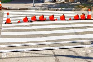 un' appena dipinto a strisce pedone attraversamento attraverso il strada è recintato via con traffico coni. foto