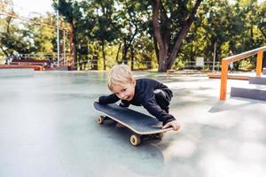 poco ragazzo provando per raccogliere su un' skateboard foto