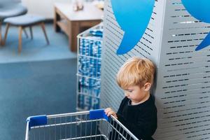 un' poco ragazzo e un' grande carrello nel il supermercato foto