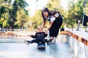 giovane madre insegna sua poco ragazzo per cavalcata un' skateboard foto