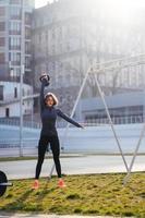 giovane donna esercizio con un' kettlebell al di fuori a stadio foto