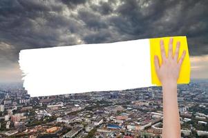 mano elimina tempesta nuvole al di sopra di città di giallo straccio foto